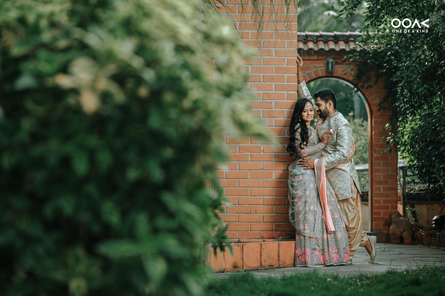 Wedding couple walking through a garden pathway lined with trees